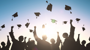 students throwing graduation hats into the ait